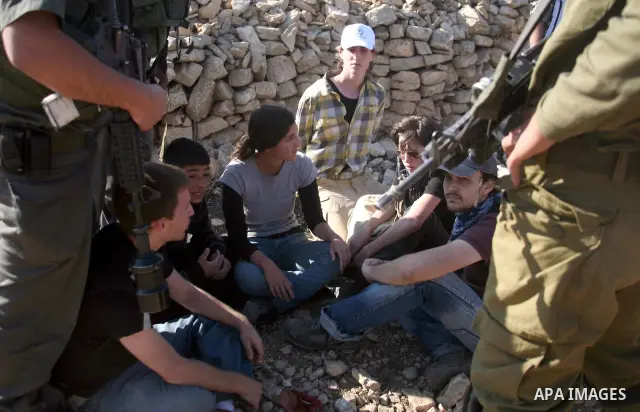 Israeli soldiers disperse foreign activists during a demonstration by Palestinian, Israeli and foreign activists against the demolishing of farm land to be used in the construction of Jewish settlements near the existing...