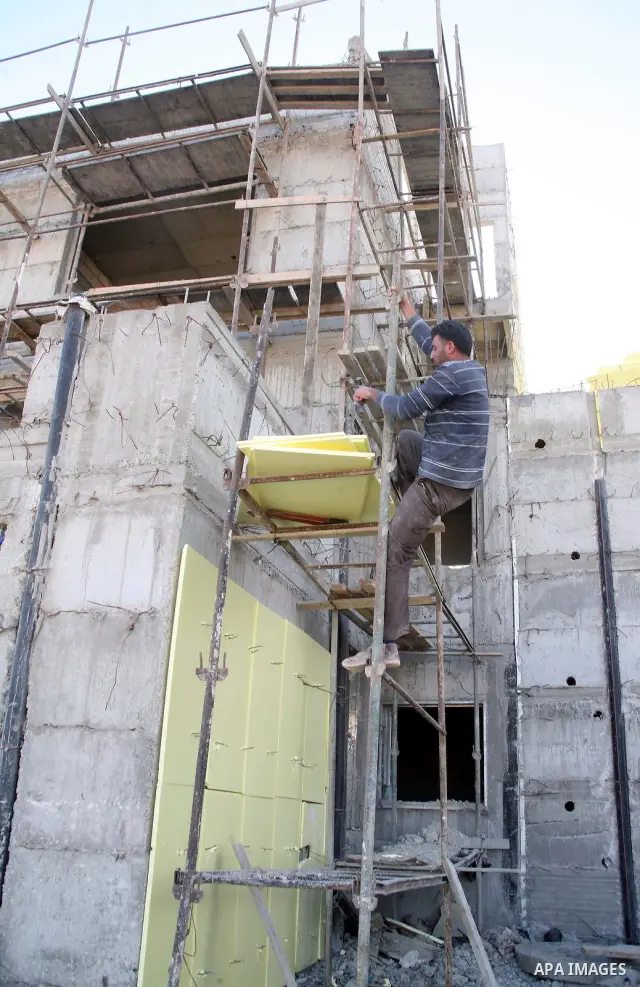 A Palestinian man works in a new housing unit in a construction site in the West Bank settlement of Kiryat Arba, near Hebron, Nov. 29,2010. Photo by Najeh Hashlamoun