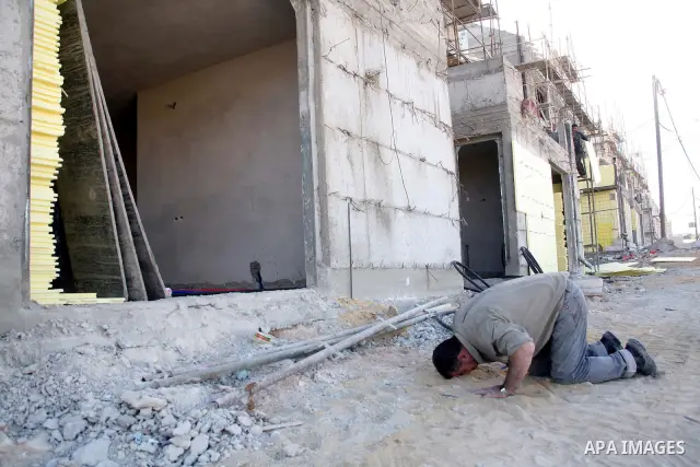 A Palestinian man works in a new housing unit in a construction site in the West Bank settlement of Kiryat Arba, near Hebron, Nov. 29,2010. Photo by Najeh Hashlamoun