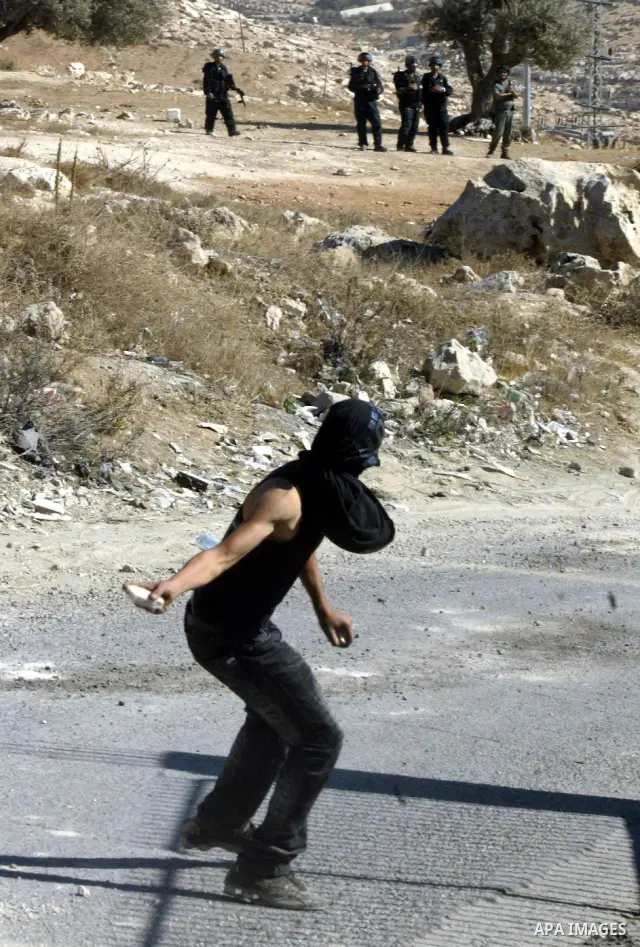 A Palestinian youth throws stones at Israeli soldiers after a house was demolished by Israeli municipality bulldozers for allegedly being built illegally in the Arab east Jerusalem neighbourhood of Issawiyah on November...