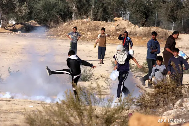 A Palestinian protester returns a tear gas canister fired by Israeli troops in the West Bank village of Nabi Saleh near Ramallah, during a demonstration against the expropriation of Palestinian land to expand the nearby...