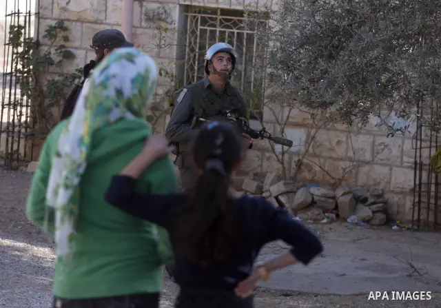 An Israeli soldier walks past Palestinian girls in the West Bank village of Nabi Saleh near Ramallah, during a demonstration against the expropriation of Palestinian land to expand the nearby Jewish settlement of Halamis...