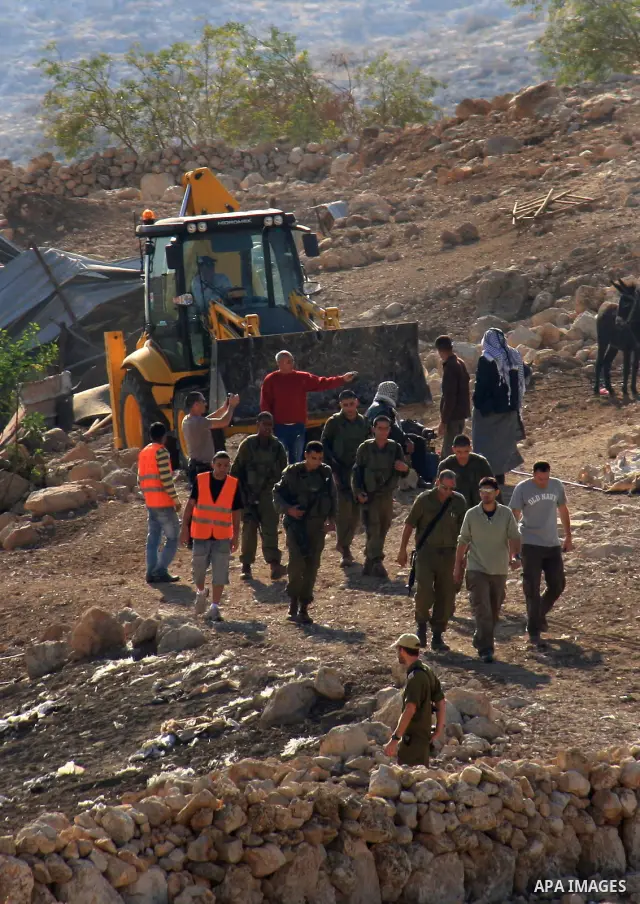 Israeli soldiers stand guard as An Israeli army bulldozer destroys a Palestinian home, in the village of Khirbet Tana near the West Bank city of Nablus, Wednesday, Dec. 8, 2010. Palestinians say Israel's military has bul...