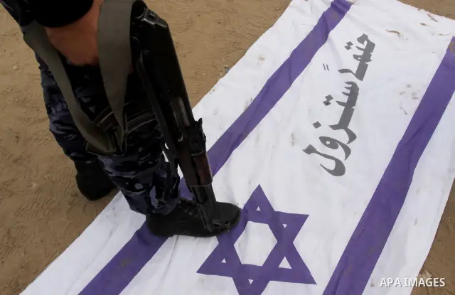 Hamas security members walk on an Israeli flag reading in Arabic "Israel will definitely disappear" as part of celebrations marking the 23rd anniversary of the Islamist movement's foundation in Gaza City on December 9, 2...
