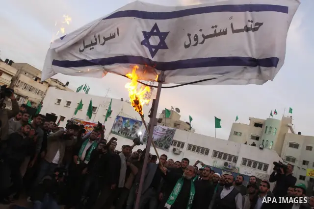 Hamas leader Mahmoud al-Zahar uses a torch to set fire to an Israeli flag reading in Arabic "Israel will definitely disappear" as part of celebrations marking the 23rd anniversary of the Islamist movement's foundation in...