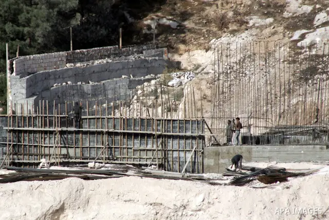 Palestinian labourers work at a construction site at the Jewish settlement in Harmoun Hanatsev in the east Jerusalem on Dec. 9,2010. The United States on Tuesday abandoned its effort to persuade Israel to freeze construc...