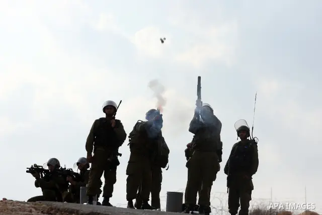 Israeli soldiers fire tear gas during a demonstration against the construction of the Israeli controversial separation barrier in the West Bank village of Bilin near Ramallah on, Dec. 10, 2010. Photo by Issam Rimawi