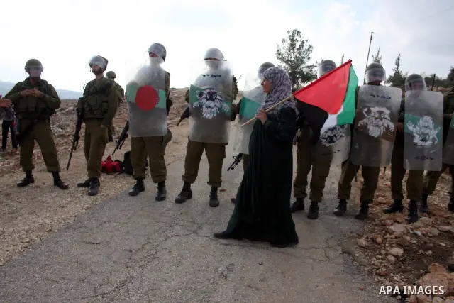 A Palestinian woman waves the Palestinian flag during a protest against the construction of the Israeli controversial separation barrier in the West Bank village of Bilin near Ramallah on, Dec. 10, 2010. Photo by Issam R...