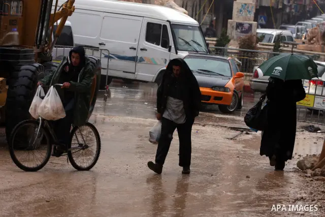 Palestinians walk in a street during the heavy rain and cold winds in the West Bank city of Ramallah on Dec. 13,2010. Photo by Issam Rimawi