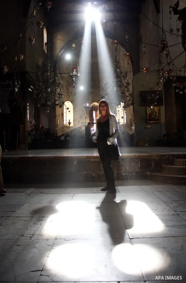 Christian pilgrims pass through a shaft of light entering the Church of the Nativity in the West Bank town of Bethlehem on December 16,2010. The light passes through an Orthodox Christian section of the church in the cen...