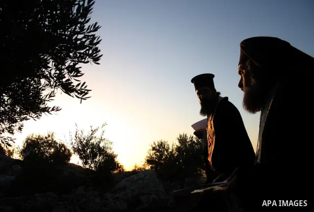 An Orthodox Christians light stand outside a cave at the ancient monastery of St. Barbara in the nearby hills close to the village of Abud, in the Israeli occupied West Bank on December 16, 2010, as they celebrate the an...