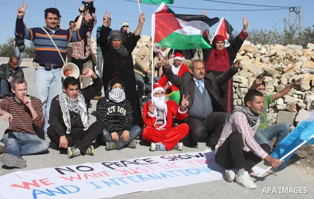 Palestinian men wear as Santa Claus during a protest by Palestinians and foreign peace activists against Israel's controversial separation barrier in the West Bank village of Maasarah near the Palestinian biblical town o...