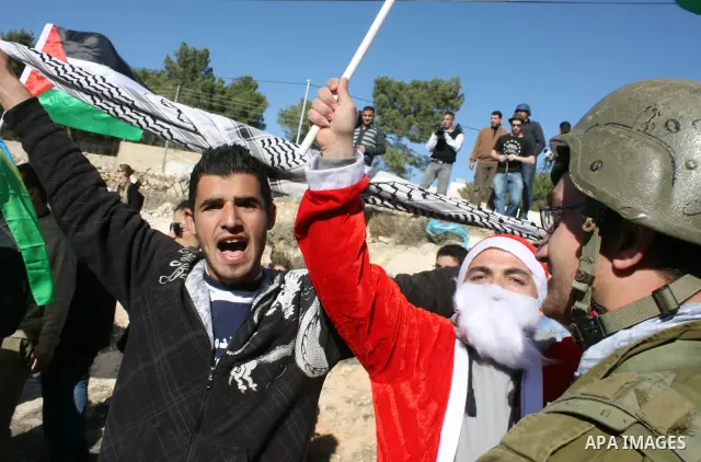 A Palestinian man wears as Santa Claus during a protest by Palestinians and foreign peace activists against Israel's controversial separation barrier in the West Bank village of Maasarah near the Palestinian biblical tow...