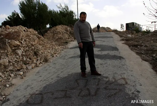 A Palestinian man passes near Hebrew text in the village of Tel near the West Bank city of Nablus, Saturday, Dec.18, 2010. Jewish settlers from Havad Kad settlement destroyed farmers crops and painted alot of slogans in...