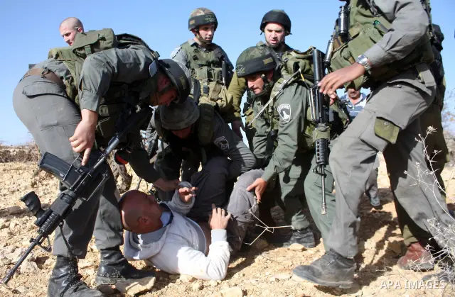 Israeli soldiers arrest a demonstrator during a protest against Israel's controversial separation barrier organized by Palestinian and foreign peace activists in the West Bank village of Beit Omar, near Hebron, on 18 Dec...
