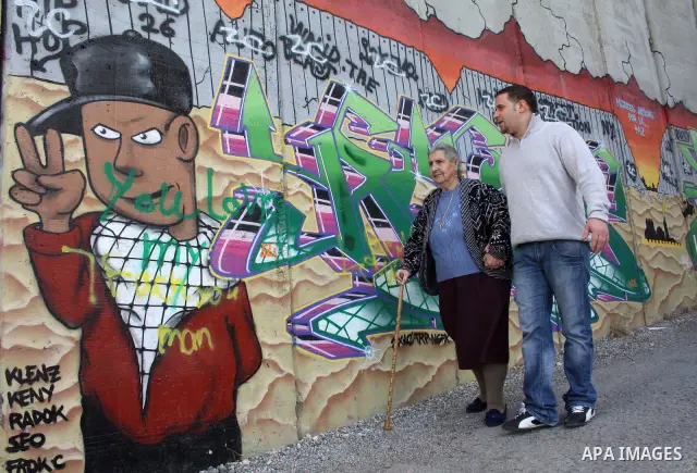 Palestinian christian woman walks past Christmas graffiti painted on the Israeli separation barrier in the West Bank town of Bethlehem, as Christmas approaches, on December 22, 2010. Photo by Najeh Hashlamoun