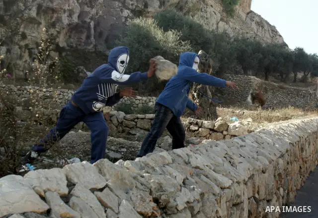 Palestinian youths throw stones towards Israeli soldiers during clashes in the Arab east Jerusalem neighbourhood of Silwan against Jewish settlement activity in the Palestinian districts of the holy city on December 24,...