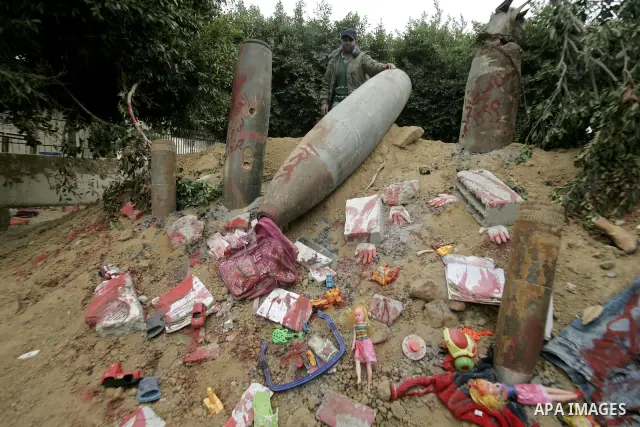 Palestinian man stands near the remains of the ammunition which was used during the war on Gaza at an exhibition organized by Hamas marks the second anniversary of Israel's three-week offensive on Gaza, in the southern G...