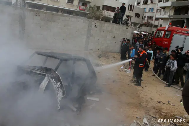 A Palestinian civil defense worker extinguishes a car that was set ablaze by Hamas supporters as he takes part in a reenactment of an Israeli strike during a performance organized by Hamas, marking the 2nd anniversary of...