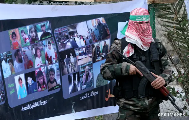A Palestinian Hamas militant stands in front of a poster to Palestinian martyrs during a rally marking the 2nd anniversary of Israeli war on Gaza Strip, in Gaza City on January 1, 2011. Photo by Mohammed Asad