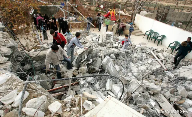 Palestinians stand on the rubble of a home after Israeli army bulldozers destroyed the house in the Arab neighborhood of Beit Hanina in occupied east Jerusalem on on Jan. 4, 2011. Photo by Mahfouz Abu Turk