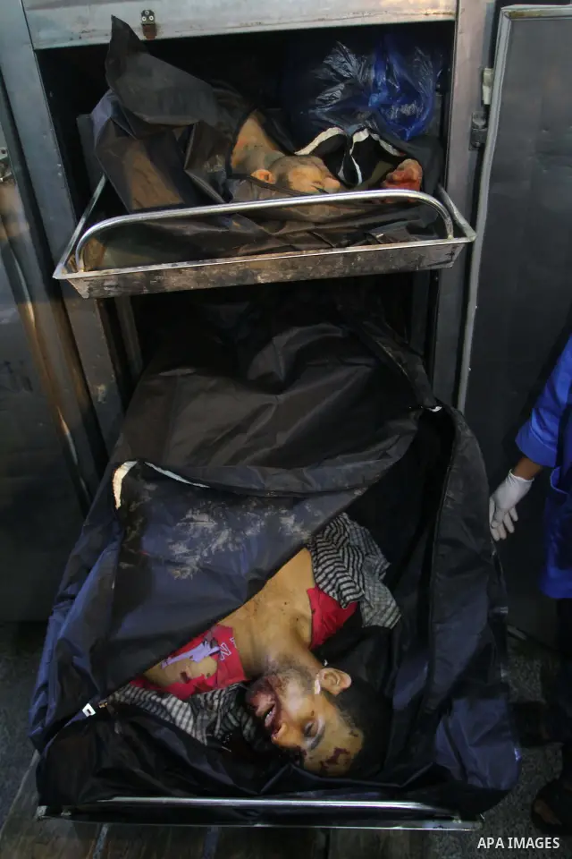 Palestinian men stand next to the bodies of two Palestinians at the morgue in the Adwan hospital in the town of Beit Lahiya, northern Gaza Strip, on January 6, 2011. Two Palestinians were killed by Israeli fire in Gaza,...