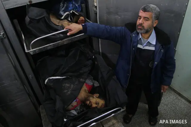 A Palestinian man stands next to the bodies of two Palestinians at the morgue in the Adwan hospital in the town of Beit Lahiya, northern Gaza Strip, on January 6, 2011. Two Palestinians were killed by Israeli fire in Gaz...
