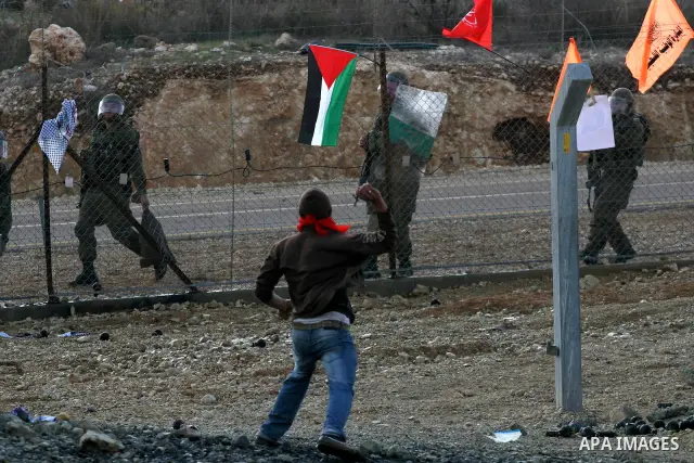 Palestinian youths hurl stones towards Israeli soldiers during a protest in the village of Bilin on January 7, 2011. Israeli troops in Hebron shot dead an elderly Palestinian civilian on Friday in a case of mistaken iden...