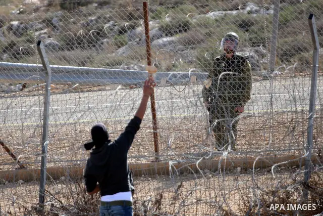 Palestinian youths hurl stones towards Israeli soldiers during a protest in the village of Bilin on January 7, 2011. Israeli troops in Hebron shot dead an elderly Palestinian civilian on Friday in a case of mistaken iden...
