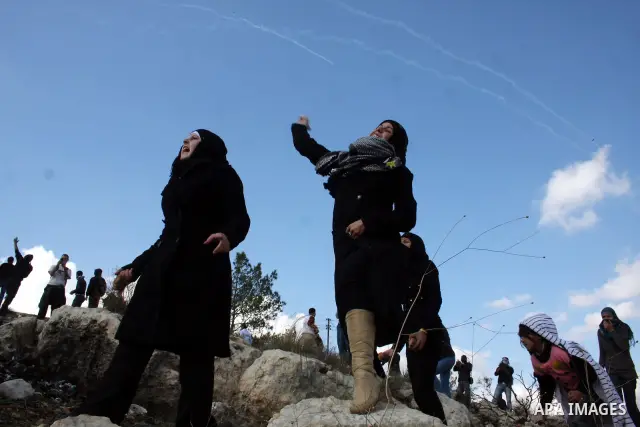 Palestinian youths hurl stones towards Israeli soldiers during a protest in the village of Bilin on January 7, 2011. Israeli troops in Hebron shot dead an elderly Palestinian civilian on Friday in a case of mistaken iden...