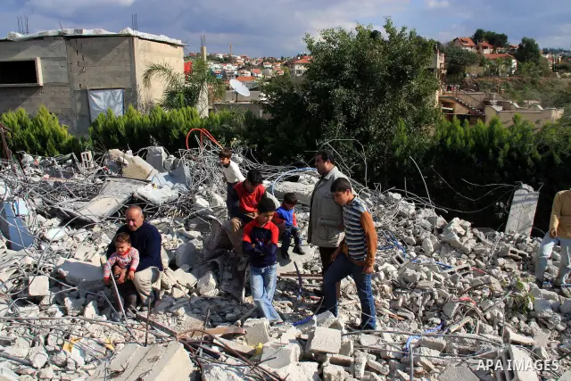 Palestinian Samer Younis family sit on the rubble of her house after Israeli troops demolished the house that was built without a construction permit in the West Bank village of Azzun Atma, near Qalqilia, Tuesday on Janu...