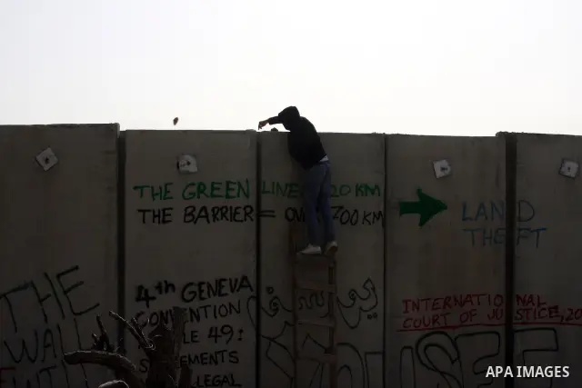 A Palestinian protester hurls a stone at Israeli troops, during a protest against Israel's separation barrier in the West Bank village of Nilin near Ramallah, Friday, Jan. 14, 2011. Photo by Issam Rimawi