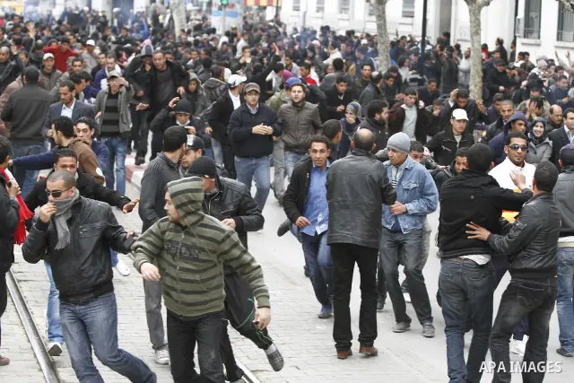Protestors run away as police use tear gas during a demonstration against Tunisia's ruling Constitutional Democratic Rally party (RCD) in the center of Tunis, Jan. 18. 2011. Tunisian interim president Foued Mebazaa and P...