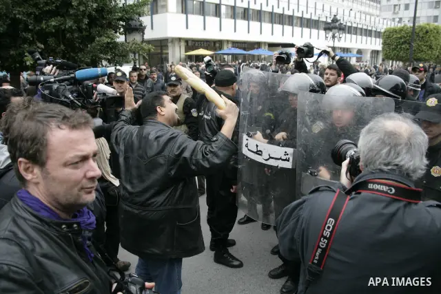 A Protestor holds bread as he face riot police officers during a demonstration against the Constitutional Democratic Rally, RCD, party of Ben Ali in the center of Tunis, Tuesday, Jan. 18. 2011. Four ministers quit Tunisi...