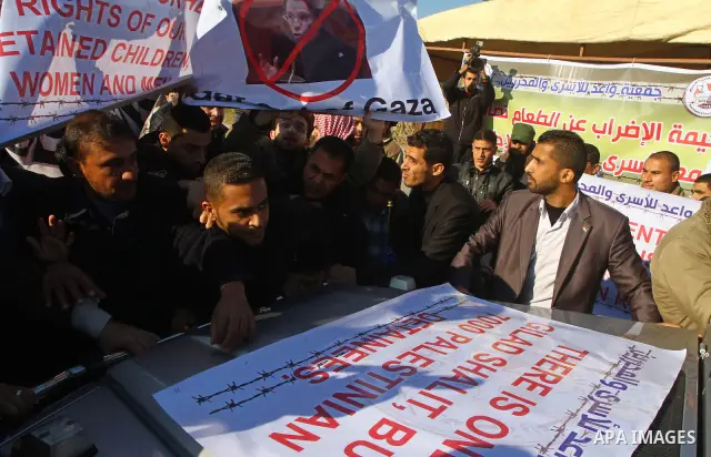 Palestinian relatives of a prisoners jailed in Israel hold posters as they block the vehicle carrying French Foreign Minister Michele Alliot-Marie as it makes its way into Gaza Strip, on the Palestinian side of the Erez...