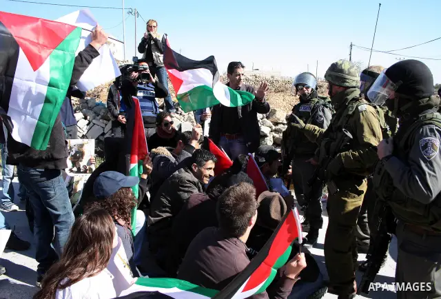 Israeli soldiers stand guard as Palestinian, Israeli and foreign protesters take part in a demonstration against Israel's controversial separation barrier in the West Bank village of Maasarah, near Bethlehem, on January...