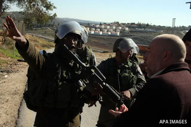 Israeli soldiers stand guard as Palestinian protesters take part in a demonstration against the expansion of the nearby Jewish settlement of Halamish in the West Bank village of Nabi Saleh, near Ramallah, Friday, Jan. 21...