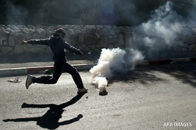 Masked Palestinian youth kicks a tear gas canister at Israeli forces during clashes in the Arab east Jerusalem neighbourhood of Silwan on January 21, 2011. Photo by Mahfouz Abu Turk