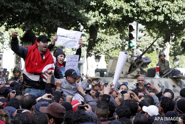 Tunisians, amongst them policemen, gather to ask for the right to form unions and better salaries as the vehicle of Tunisian interim President Fouad Mbazaa (not in picture) arrives at the government Palace in Tunis, Tuni...