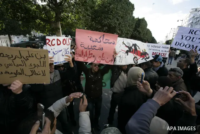 Tunisians, amongst them policemen, gather to ask for the right to form unions and better salaries as the vehicle of Tunisian interim President Fouad Mbazaa (not in picture) arrives at the government Palace in Tunis, Tuni...