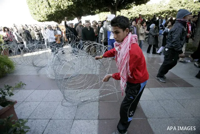 Tunisian protestors prepare to break into the barbed wire during a demonstration to demand a new government free of officials of the ousted regime of former president Zine el Abidine Ben Ali, in central Tunis, Tunisia, 2...