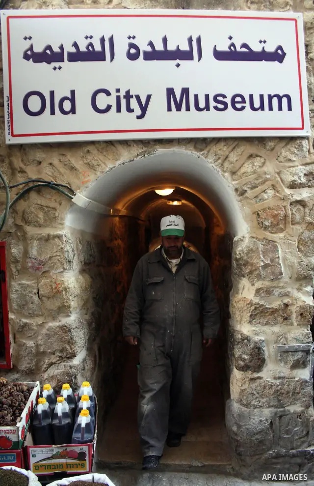 A Palestinian laborer walks near a callgraphic works during the opening of the ( Old City Museum ) in the old city of the West Bank city of Hebron on January 25, 2011. The museum located in " Haret Dari " near the Khan a...
