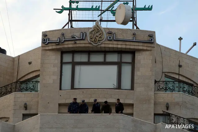 Palestinian security forces stand guard as supporters of the President Mahmoud Abbas gather next to Al-Jazeera office in the West Bank town of Ramallah, to protest against Al-Jazeera TV Channel on 25 January 2011. Palest...