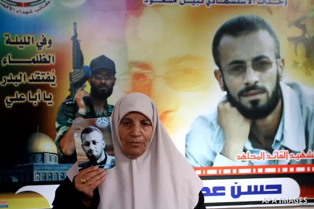 The mother of senior Fatah military commander Hassan al-Madhoun holds a picture of her son inside his family's house in Jabalya in the northern Gaza Strip Jan. 26, 2011. Thousands of protestors marched in Jabalya refugee...