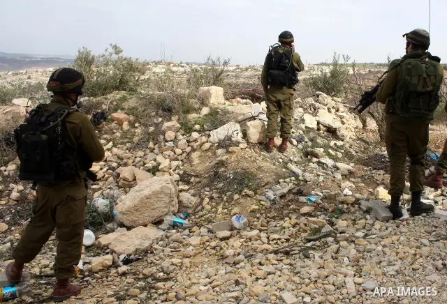 Israeli soldiers stand guard during a demonstration by Palestinian, Israeli and foreign activists against the demolishing of farm land to be used in the construction of Jewish settlements near the existing Israeli settle...