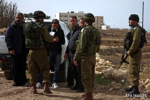 Israeli soldiers stand guard during a demonstration by Palestinian, Israeli and foreign activists against the demolishing of farm land to be used in the construction of Jewish settlements near the existing Israeli settle...