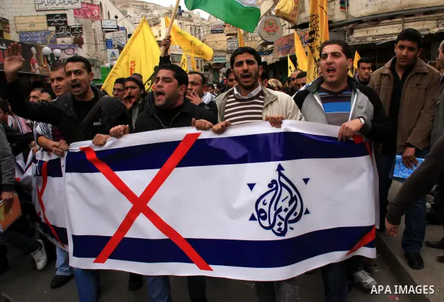 Palestinians hold Al-Jazeera logos printed in an Israeli flag during a rally in the West Bank City of Nablus , to protest against Al-Jazeera TV Channel on 27 January 2011. Al-Jazeera, a Qatar-based Arab satellite station...