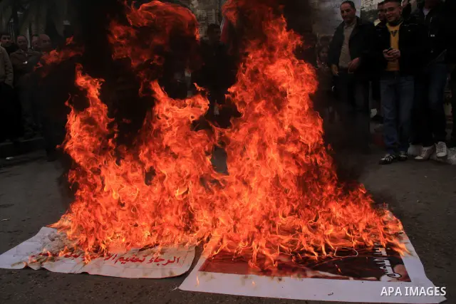 Palestinian Fatah activists burn posters of Palestinian Hamas leaders Khaled Meshaal and Mahmoud Zahar covered by printed footsteps during a rally in the West Bank City of Nablus , to protest against Al-Jazeera TV Channe...