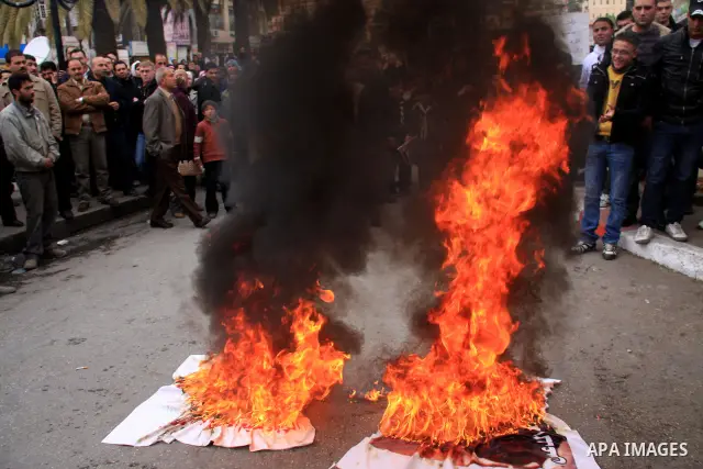 Palestinian Fatah activists burn posters of Palestinian Hamas leaders Khaled Meshaal and Mahmoud Zahar covered by printed footsteps during a rally in the West Bank City of Nablus , to protest against Al-Jazeera TV Channe...