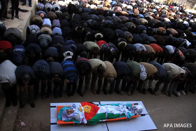 Palestinians pray next to the body of Uday Qadous, 18, who was shot and killed Thursday in the village of Iraq Burin, during his funeral at in the West Bank city of Nablus, Friday Jan. 28, 2011. Israeli police spokesman...